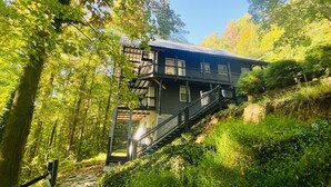 Un rustico chalet in legno con una scala che conduce a un patio, immerso nel verde.