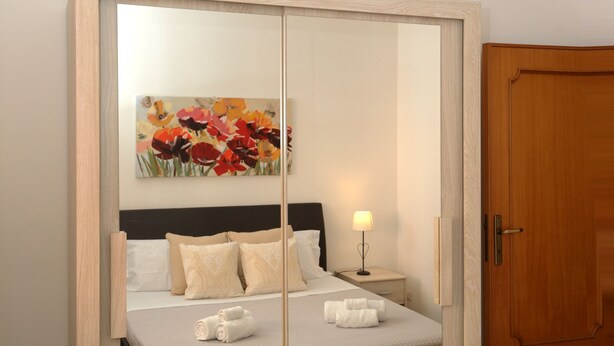 Une chambre à coucher avec un lit, une table de chevet, une lampe, un tableau et une armoire en bois.