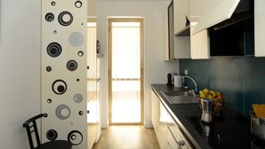 Une cuisine compacte au design moderne, comprenant un évier, une cuisinière et un petit plan de travail agrémenté de fruits et d’une machine à café.