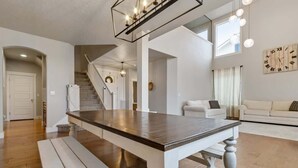Ampla sala de estar com mesa de jantar, escada e sofá.