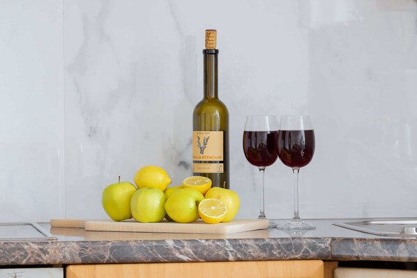A bottle of wine, two glasses, and several lemons on a kitchen counter. - Stylish Apartment with Balcony | Close to Mountain Trails (Zakopane)