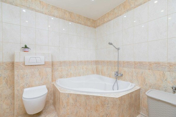 Un baño moderno con una bañera independiente, inodoro y zona de ducha.