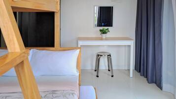 A room with a bunk bed, a desk, a chair, and a potted plant.