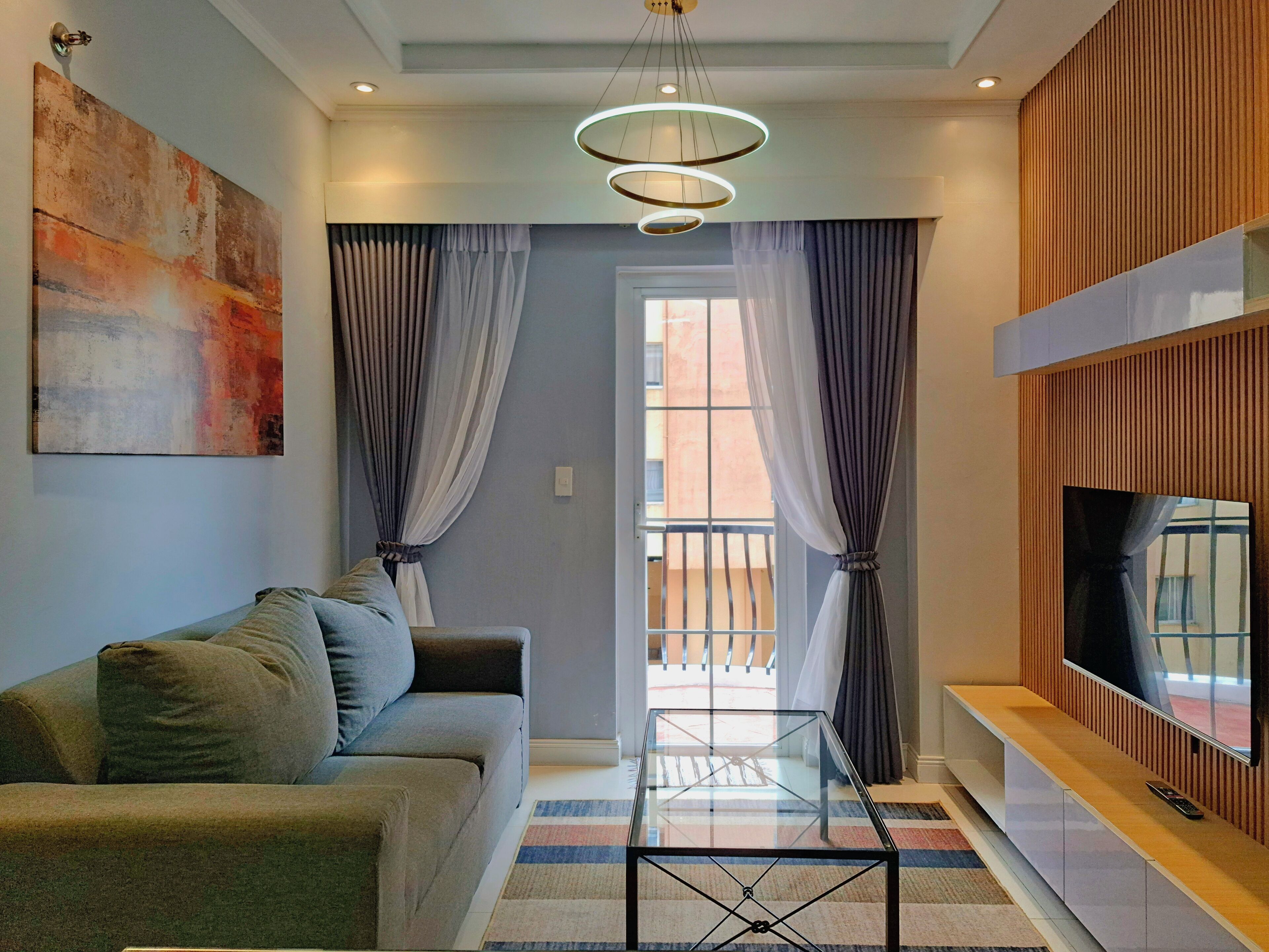 A modern living room with a sofa, a glass coffee table, and a TV on a wooden stand.
