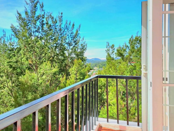 A balcony with a railing overlooking a forested area and distant mountains. - Prestige Vacation Apartments 88 Gibratar (Baguio)