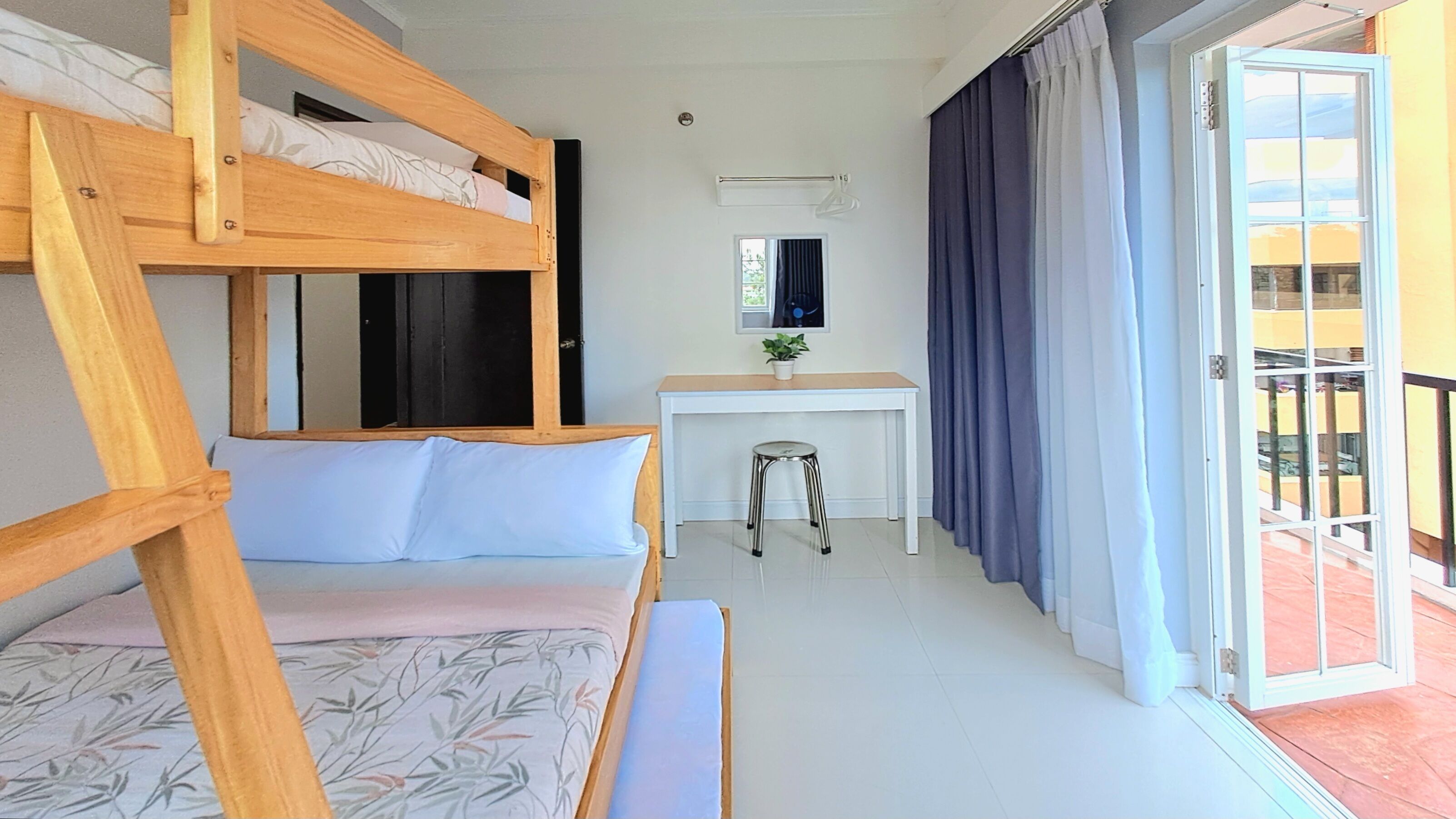 Una litera con escritorio y silla, una ventana pequeña y un panel corredizo hacia un área exterior.