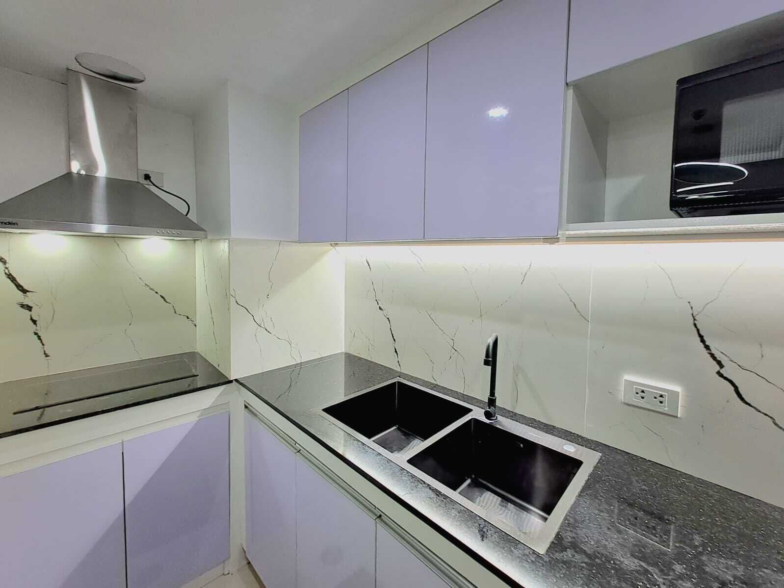 Cocina moderna con campana extractora de acero inoxidable, dos fregaderos y salpicadero de mármol.