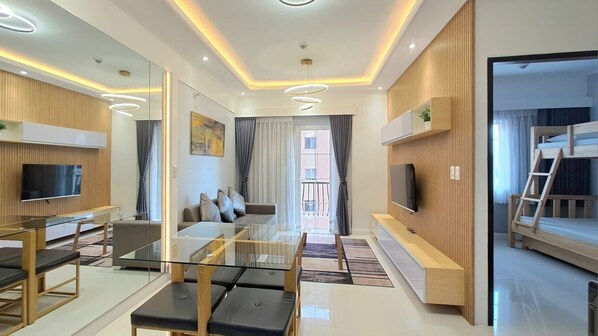 A modern living room with a glass coffee table, a sofa, and a TV mounted on the wall.