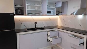 A modern kitchen with white cabinets, a black countertop, and built-in appliances including a refrigerator, microwave, and stove.