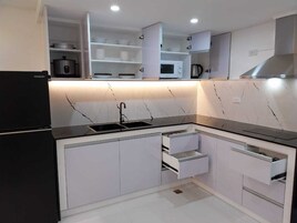 A modern kitchen with white cabinets, a black countertop, and built-in appliances including a refrigerator, microwave, and stove.