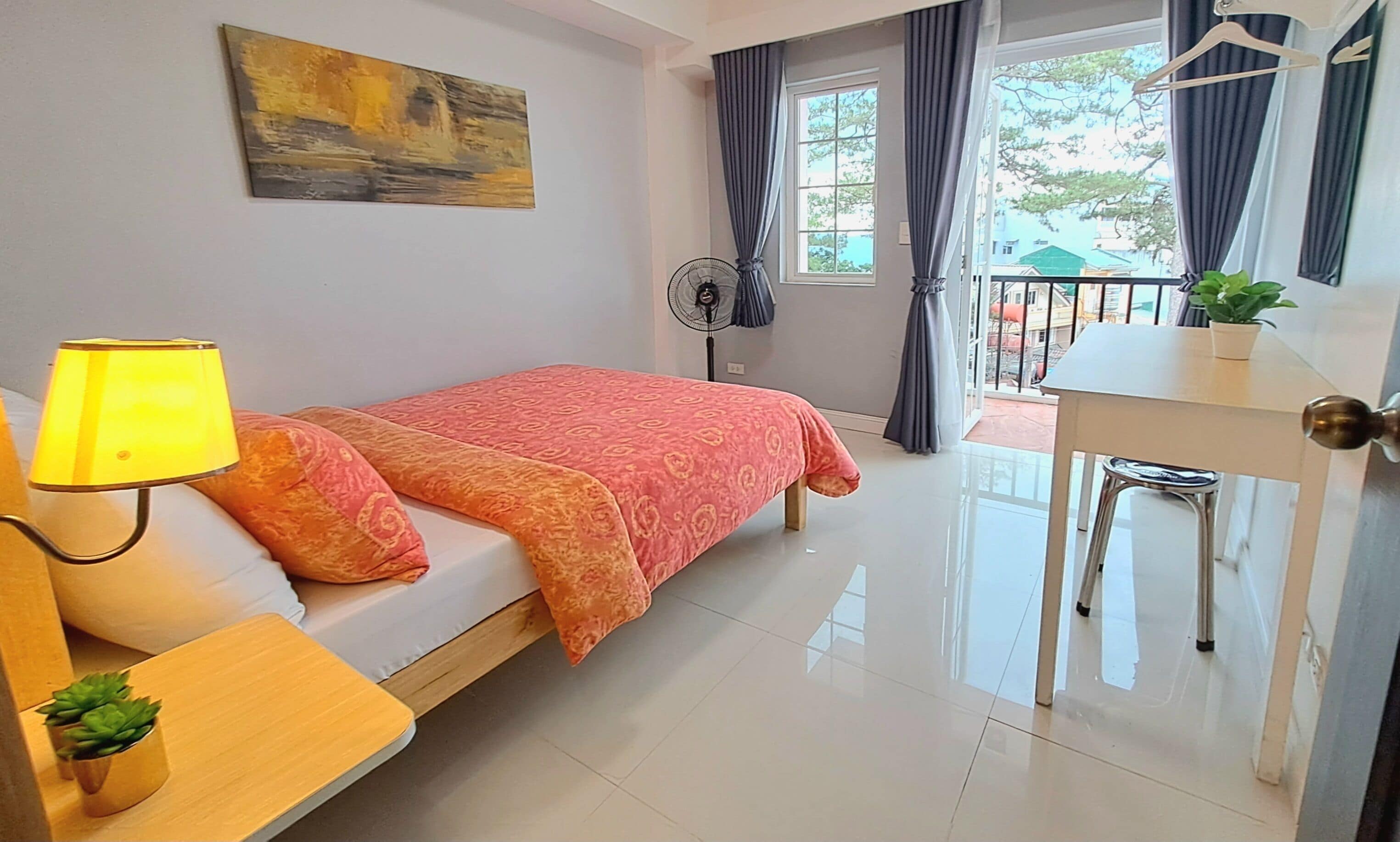 A bedroom with a bed, bedside table, lamp, and a small potted plant.