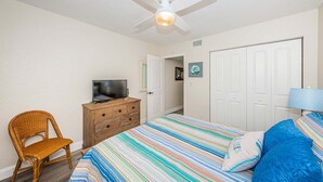 A bedroom with a bed, a television on a dresser, a chair, a door, and a ceiling fan. - Club Bahia Happiness Comes in (St. Petersburg)