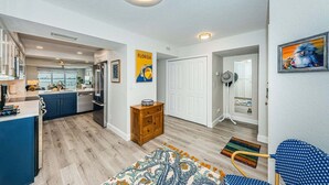 A modern kitchen with a central island, a dining area with a patterned rug, and a hallway with a door and a fan. - Club Bahia Happiness Comes in (St. Petersburg)