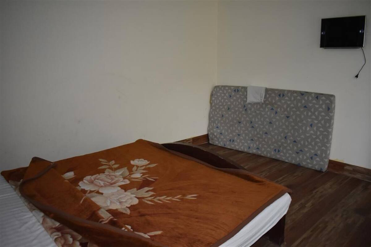 A room with a bed, a wooden headboard, and a wall-mounted TV.