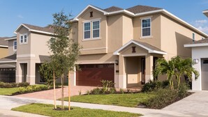 A row of townhouses with a central garage, front yard landscaping, and a clear sky. - Fantastic vacation with a private pool - FENCED POOL - Pet friendly (Kissimmee)
