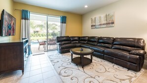 A living room with a leather sectional sofa, a glass coffee table, and a TV mounted on the wall. - Fantastic vacation with a private pool - FENCED POOL - Pet friendly (Kissimmee)