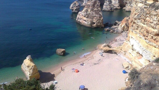 Una playa costera con acantilados rocosos y aguas azul turquesa.