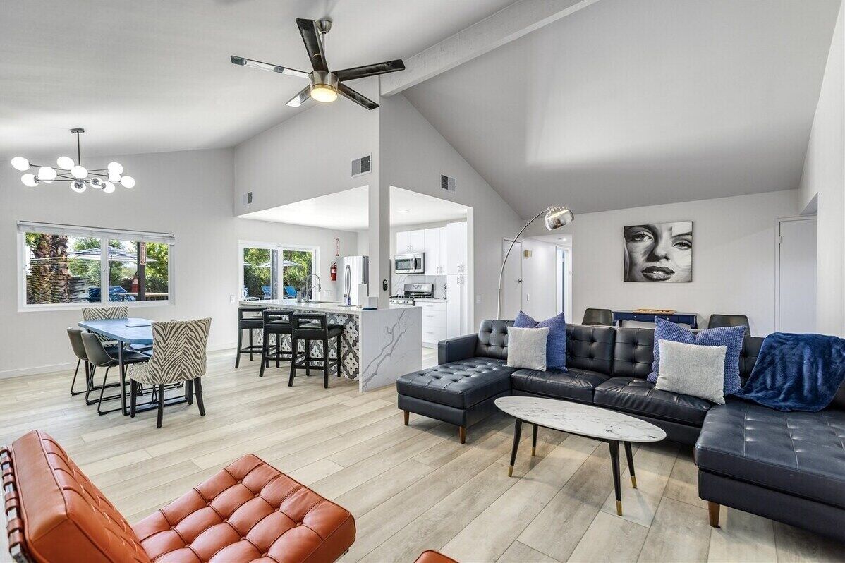 A spacious living area with a modern sofa, a dining table, and a kitchen in the background.