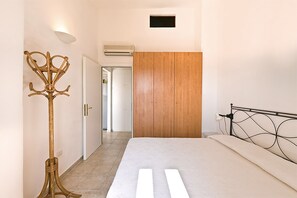 Ein Schlafzimmer mit einem Bett, einem Holzschrank, einer Wandklimaanlage und einer Stehlampe.