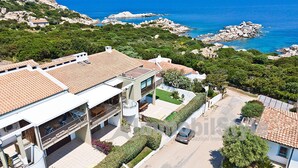 A coastal property with a spacious patio, a swimming pool, and a view of the sea.