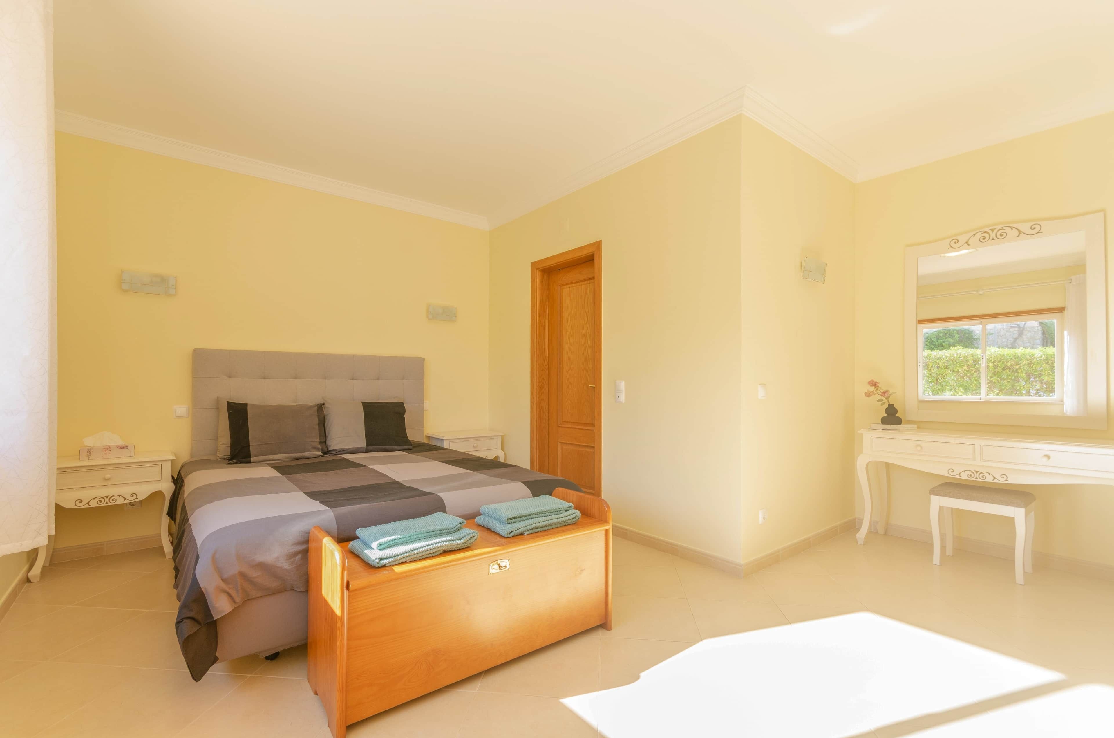 Une chambre à coucher comprenant un lit, une table de chevet, une commode et une fenêtre donnant sur un paysage agréable.