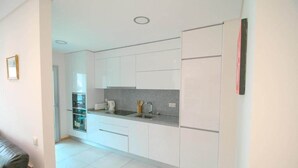 Een moderne keuken met witte kastjes, een grijze aanrechtblad en een roestvrijstalen koelkast.