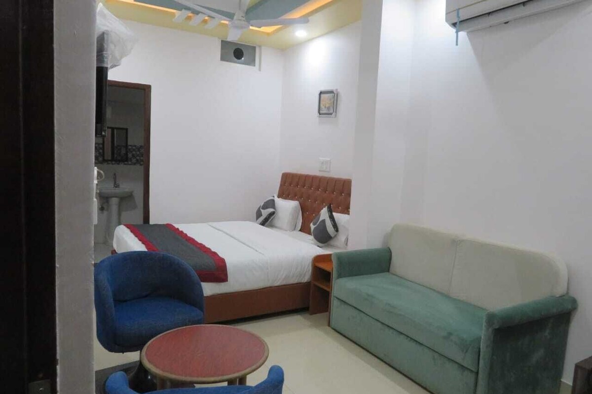 Ein Schlafzimmer mit einem Bett, einem grünen Sofa, einem blauen Sessel und einem kleinen runden Tisch.