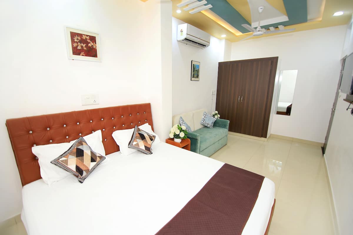 A hotel room with a large bed, a sofa, a wardrobe, and a ceiling fan.