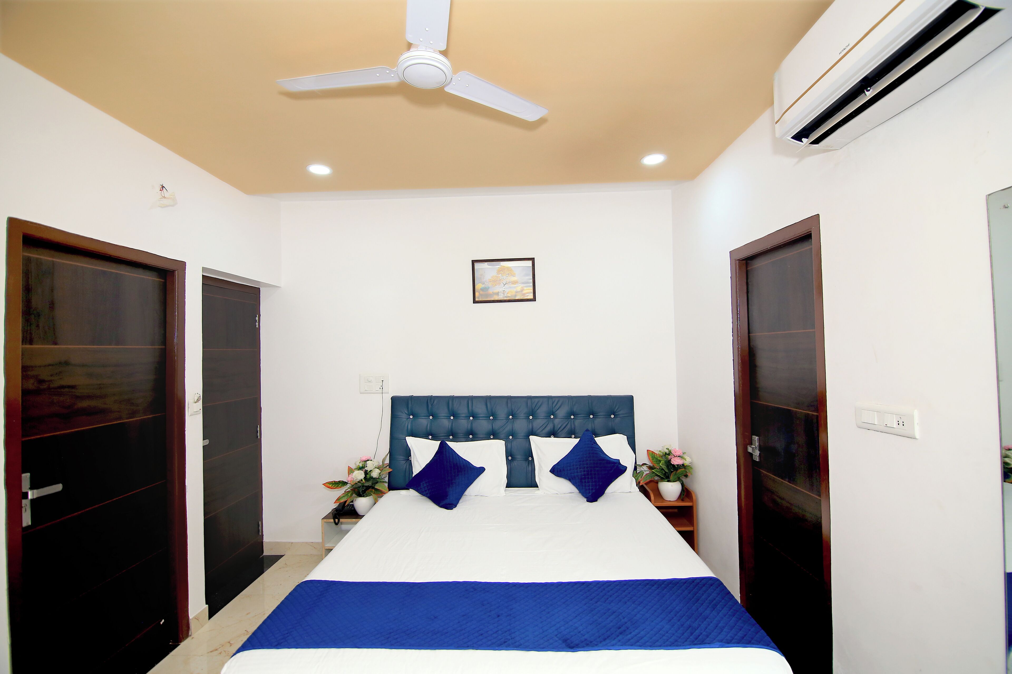 Quarto com cama, ventilador de teto, ar condicionado e duas portas.