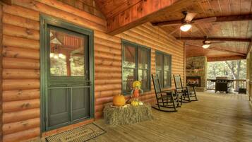 A log cabin with a fireplace, rocking chairs, and a hay bale decoration.