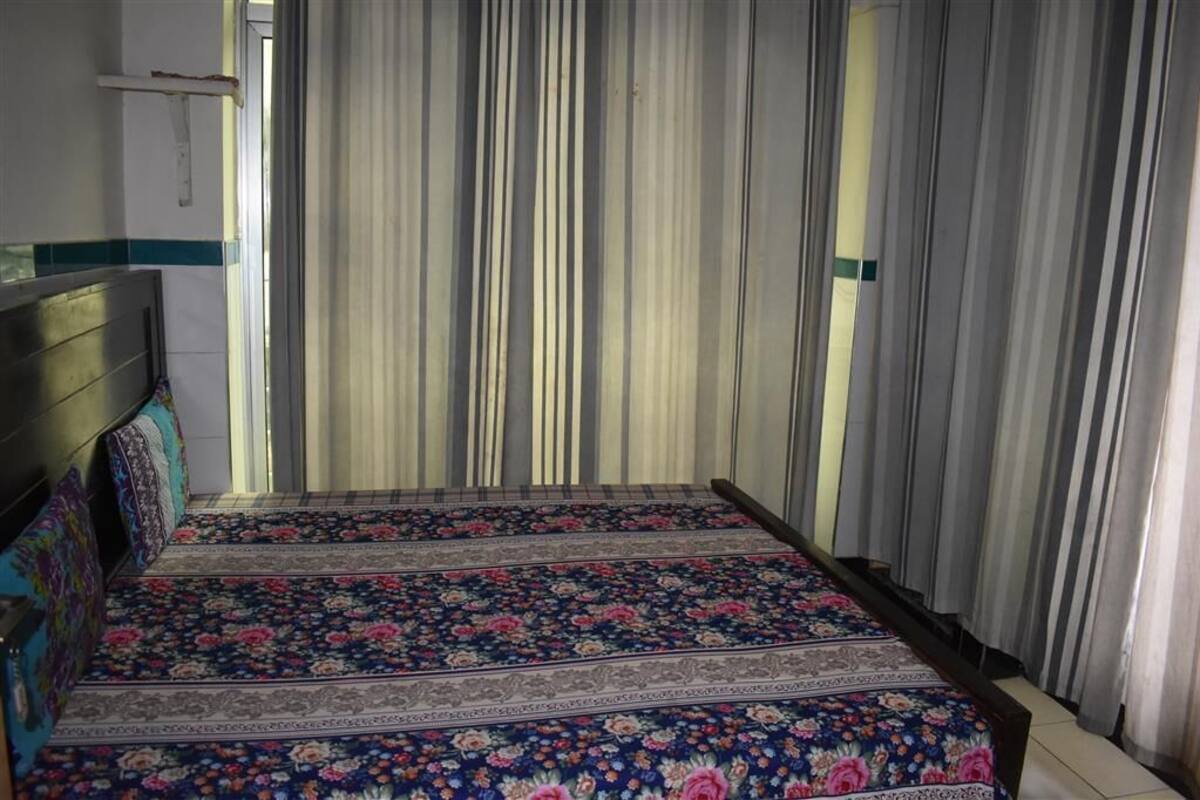 Una cama con un edredón estampado con motivos florales, un cabecero y cortinas.