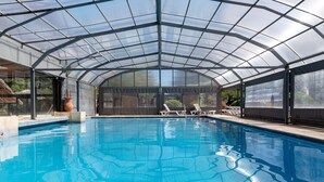 A swimming pool with a glass enclosure, lounge chairs, and a large vase. - Terranova Glamping (Luján)