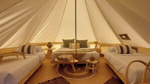 A tent with two beds, a central table with towels, and a small stool. - Terranova Glamping (Luján)