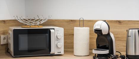 Eine Küche mit Mikrowelle, Kaffeemaschine und Papierhandtuchhalter auf einer Holzausziehtischplatte.