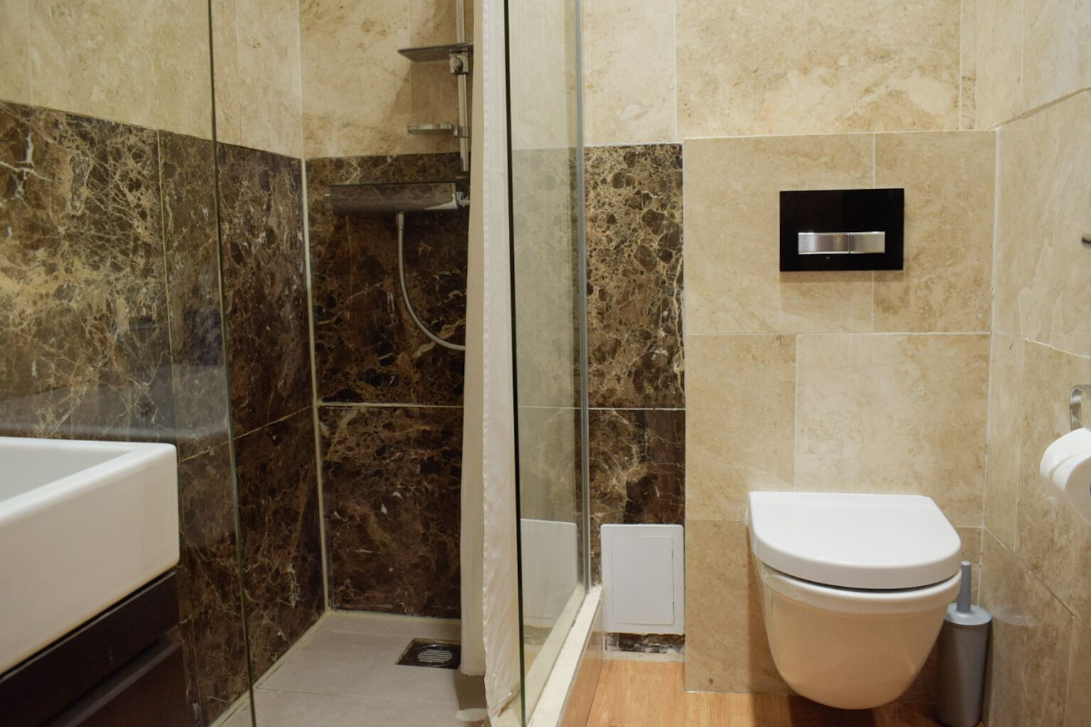 Een badkamer met douche, toilet en wastafel.