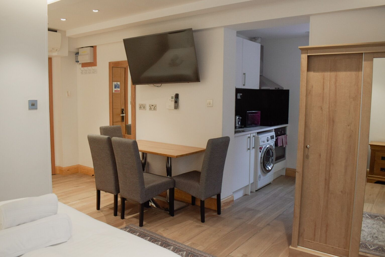 Un espacio habitable compacto con comedor, lavadora y televisor montado en la pared.