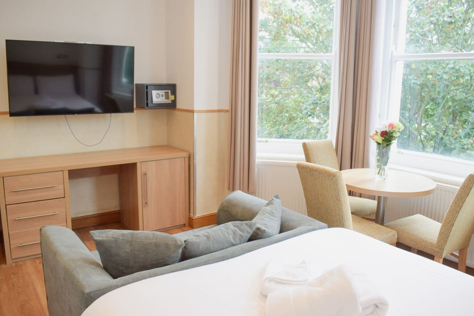 A hotel room with a bed, a TV, a desk, and a chair.