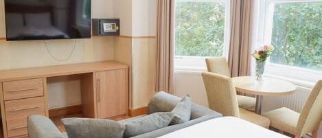 A hotel room with a bed, a TV, a desk, and a chair.