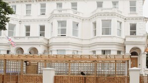 A large, white, multi-story building with a symmetrical facade, featuring arched windows and decorative moldings. - Osborne Apartments (Eastbourne)