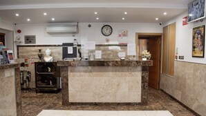 A reception area with a marble counter, a clock, and a framed picture on the wall. - Osborne Apartments (Eastbourne)