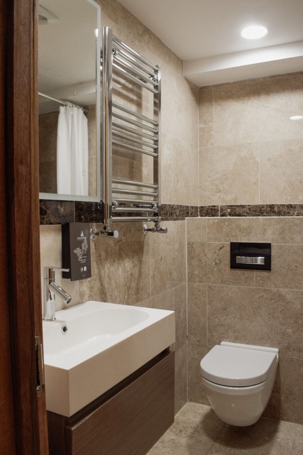 A modern bathroom with a large sink, a mirror, a towel rack, and a toilet.