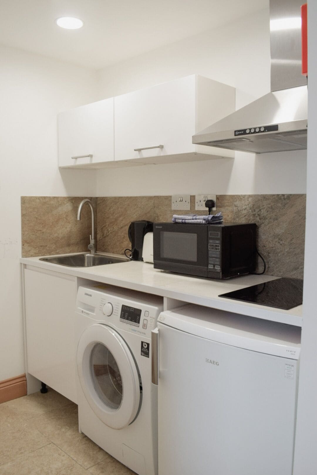 A compact kitchen with a washing machine, a microwave, and a sink.