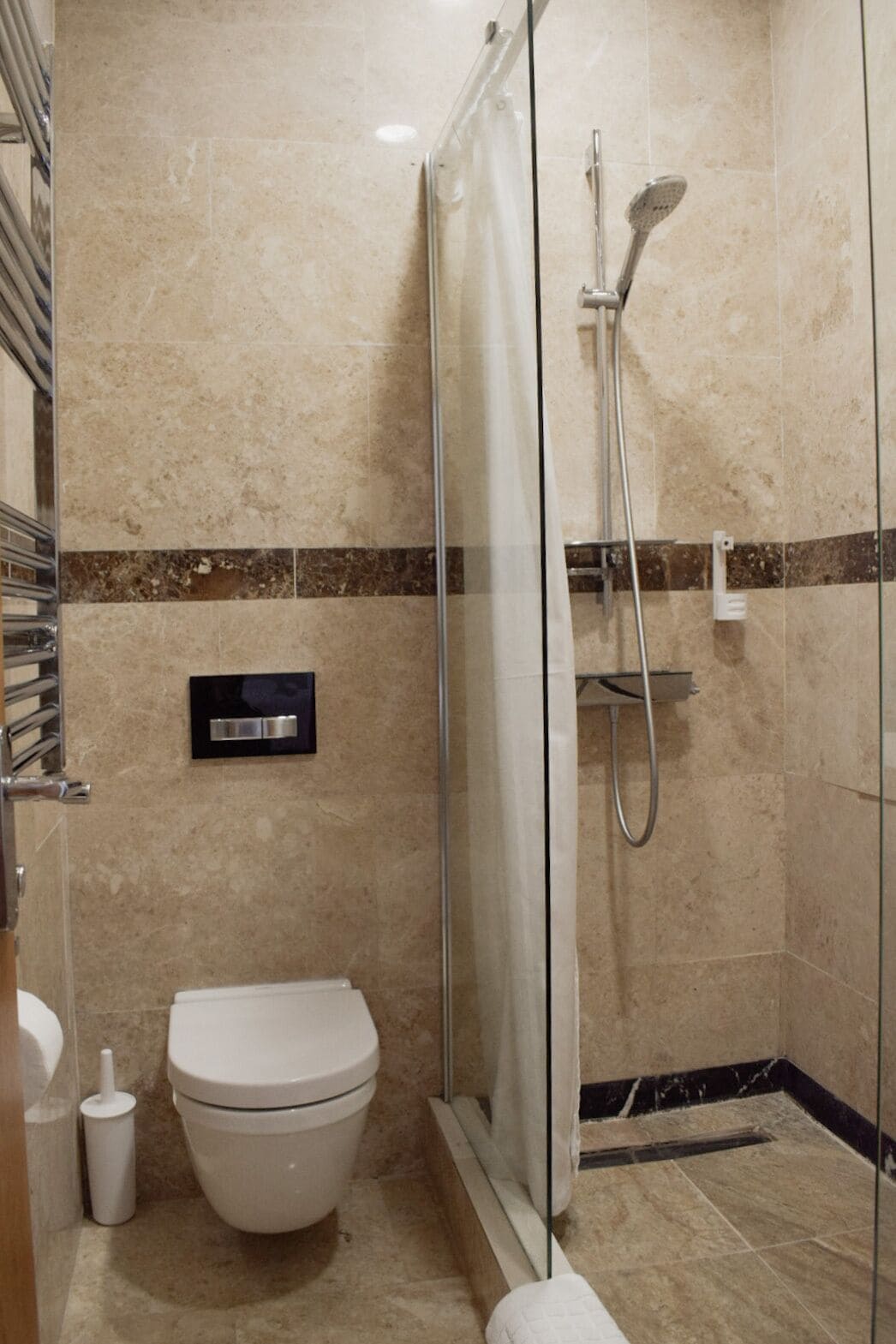 A modern bathroom with a glass-enclosed shower, a toilet, and a towel rack.