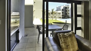 Un saló modern amb un sofà de cuir, un coixí de pell i vista a una piscina i edificis a l'exterior.