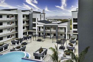 Un hôtel moderne doté de nombreux balcons, d’espaces extérieurs aménagés et d’une piscine.
