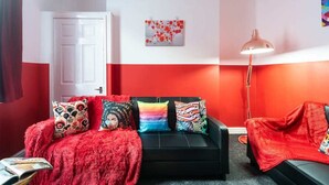 Ein Zimmer mit einer schwarzen Couch, roten Wänden und einer weißen Tür.