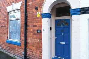 A brick building with a blue door and a window with frosted glass.