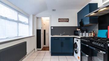 A modern kitchen with a built-in washing machine, a stove, and a microwave.