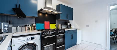 A modern kitchen with a washing machine, stove, microwave, and cabinets.
