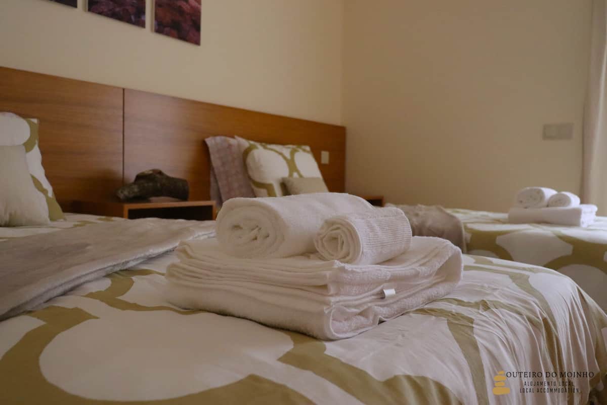 A hotel room with two beds, neatly folded towels, and a wooden headboard.
